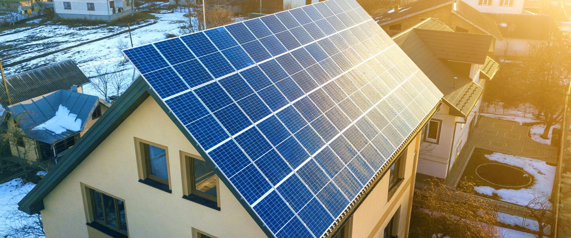 Aerial top view of new modern residential two story house cottage with blue shiny solar photo voltaic panels system on roof. Renewable ecological green energy production concept.